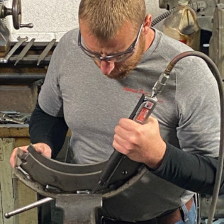 A man using a Superior Pneumatic needle scaler to remove slag from a weld